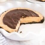 A Buckeye pie with a chocolate topping and chocolate crust in a white fluted pie dish, with one slice removed.