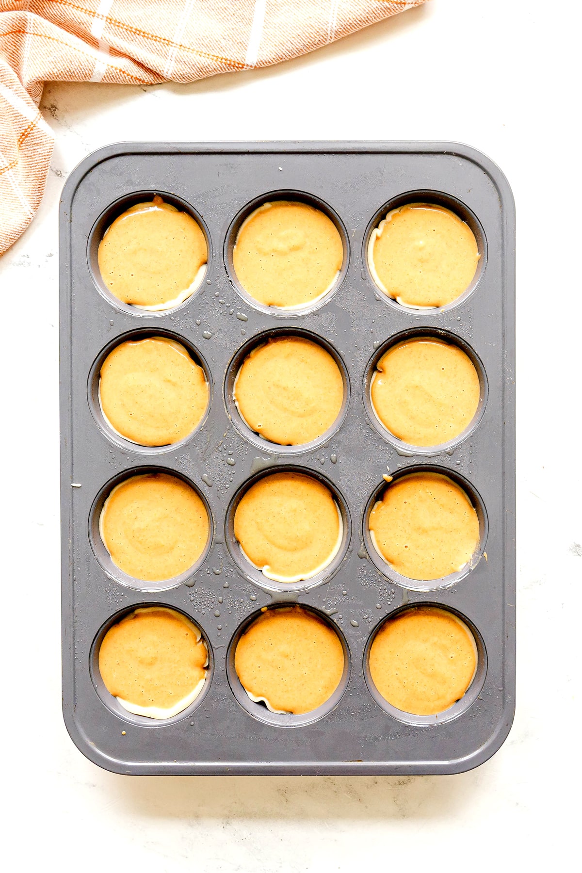 Next step in preparing Mini Pumpkin Pies is to divide the batter in each pie crust.