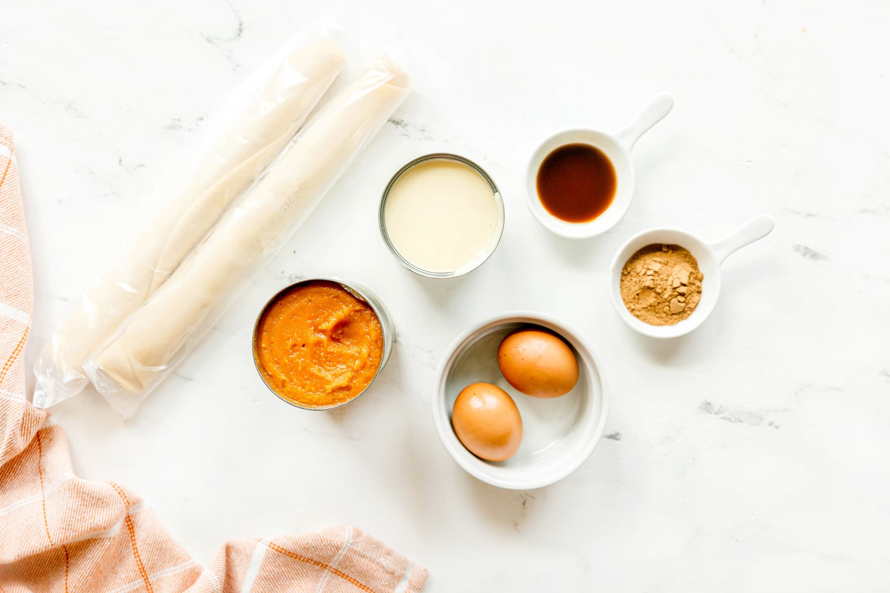 Ingredients for Mini Pumpkin Pies recipe include: two rolls of pie crust, a can of pumpkin puree, a can of sweetened condensed milk, two eggs, pumpkin pie spice and vanilla extract.