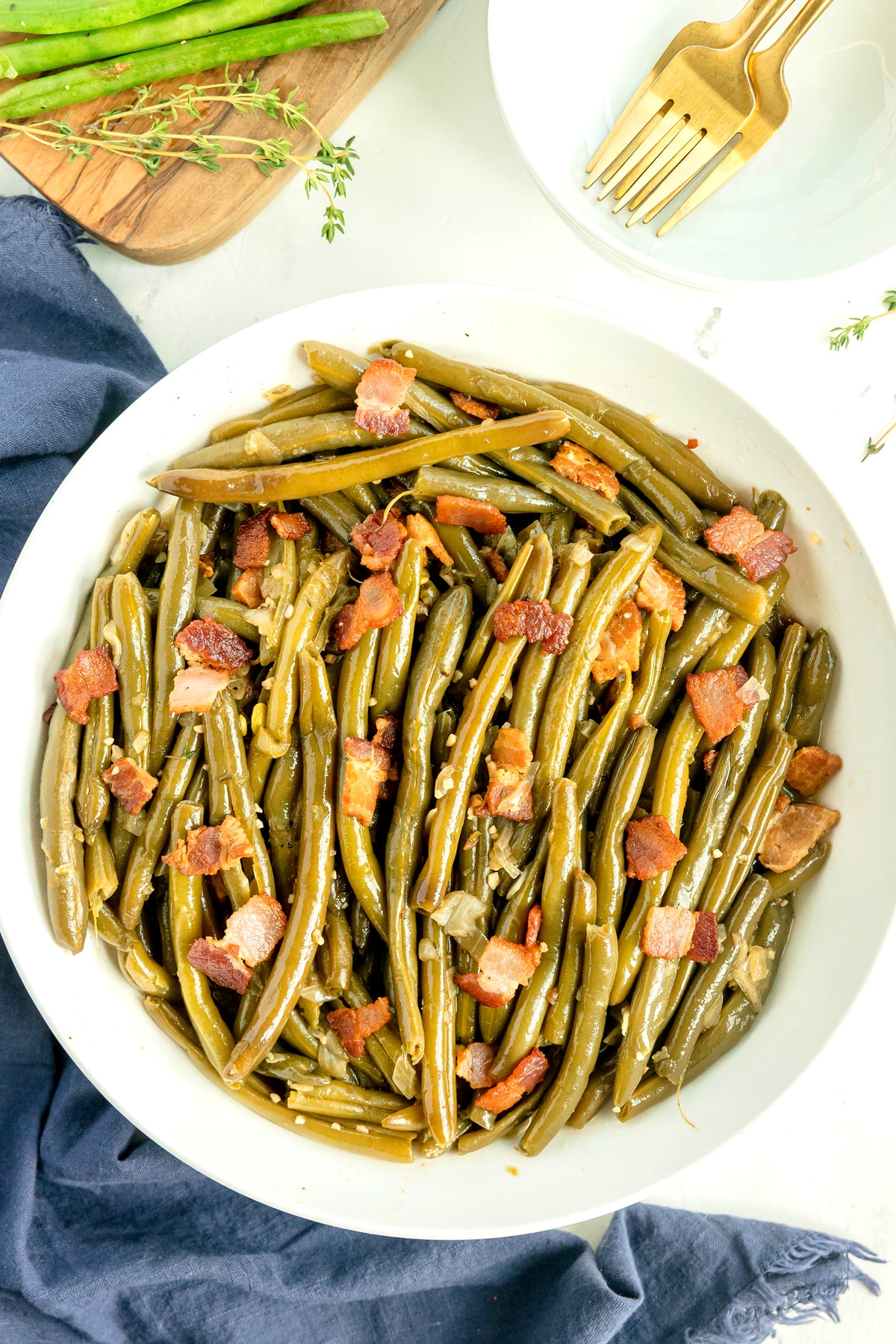 A white bowl filled with cooked Southern Green Beans and pieces of crispy bacon.