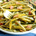 A gold fork lifting Southern Green Beans with bacon pieces.
